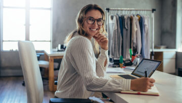 Smiling young woman taking note of orders from customers. Dropshipping business owner working in her office.